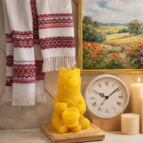 Home decor arrangement with embroidered towels, candles, framed art, books, wooden boards, and vases on a shelf.