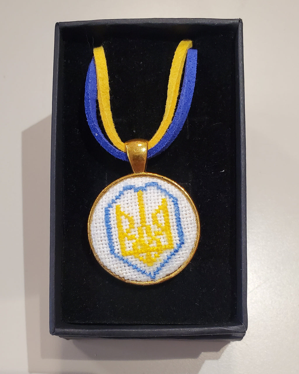 Metal pendant on a rope or chain which micro-embroidered name codes