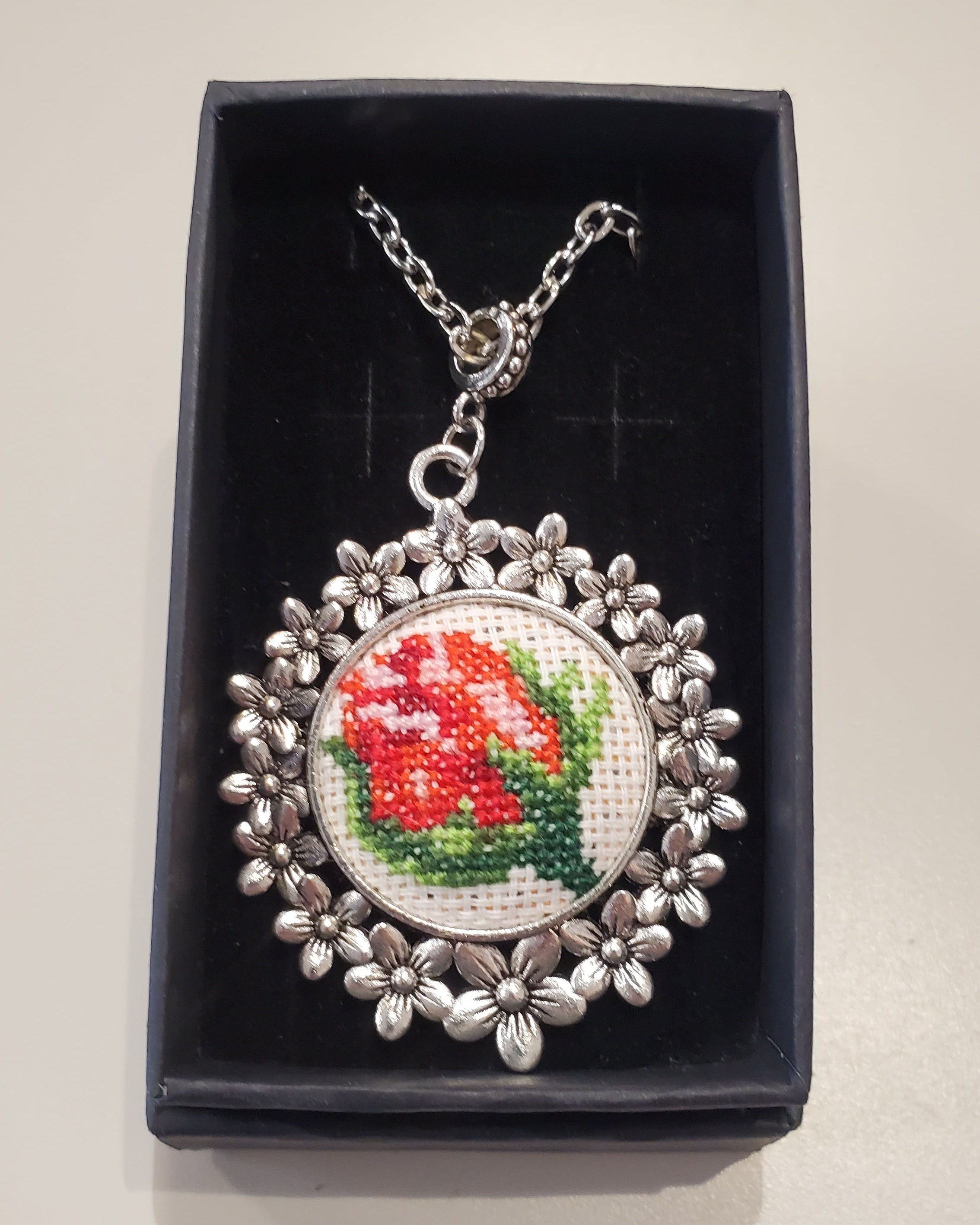 Metal pendant on a rope or chain which micro-embroidered name codes