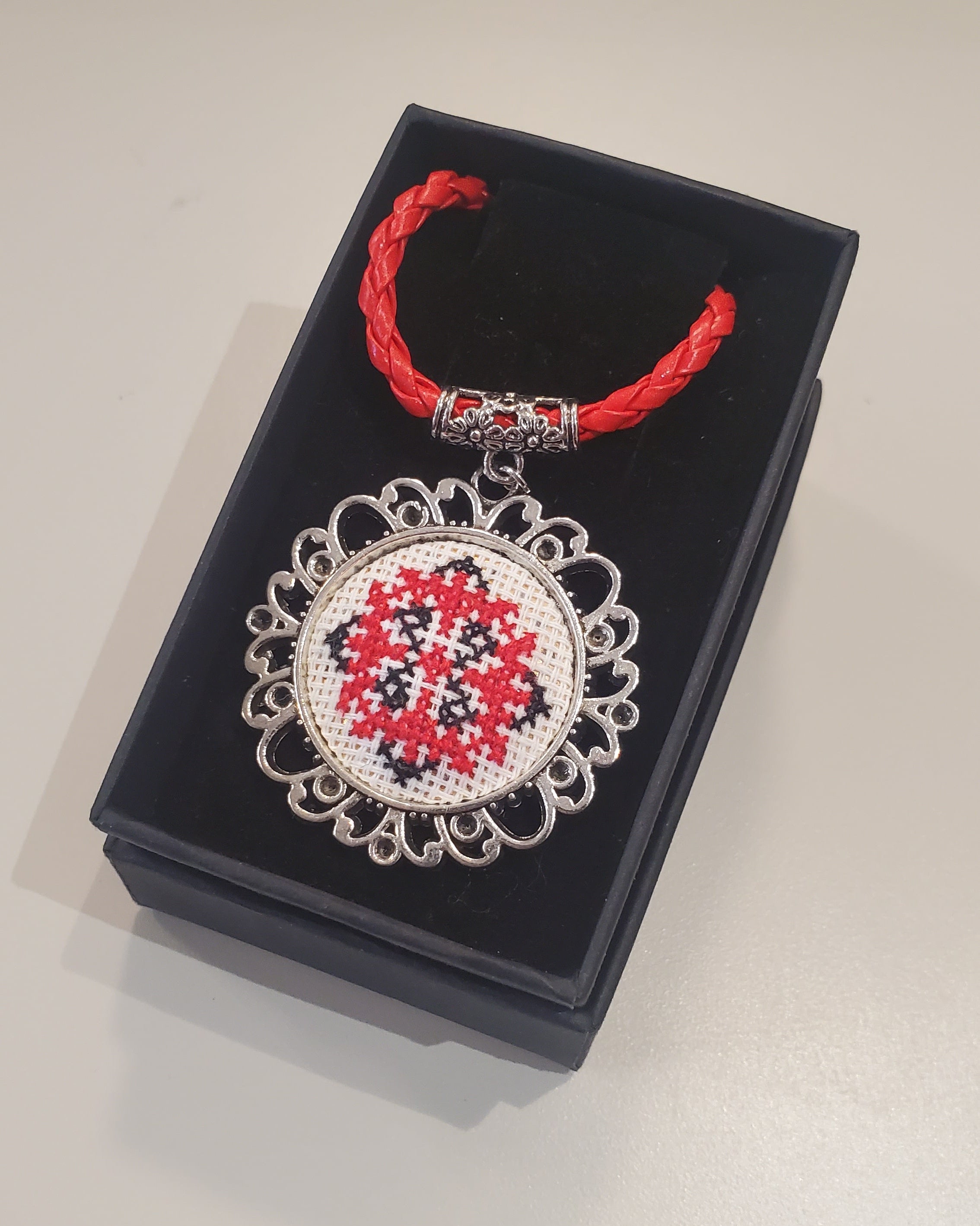 Metal pendant on a rope or chain which micro-embroidered name codes