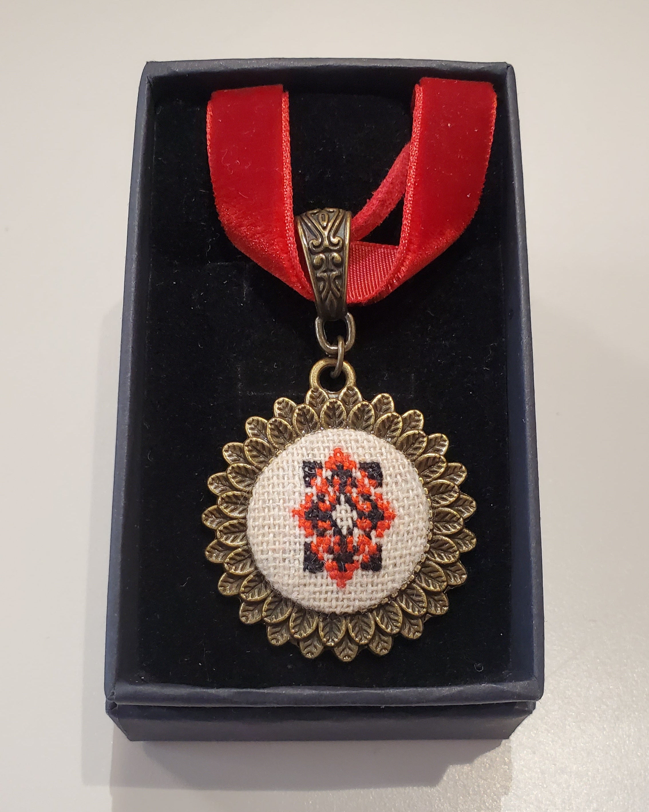 Metal pendant on a rope or chain which micro-embroidered name codes