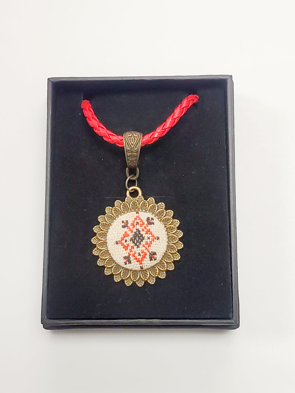 Metal pendant on a rope or chain which micro-embroidered name codes