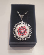 Metal pendant on a rope or chain which micro-embroidered name codes
