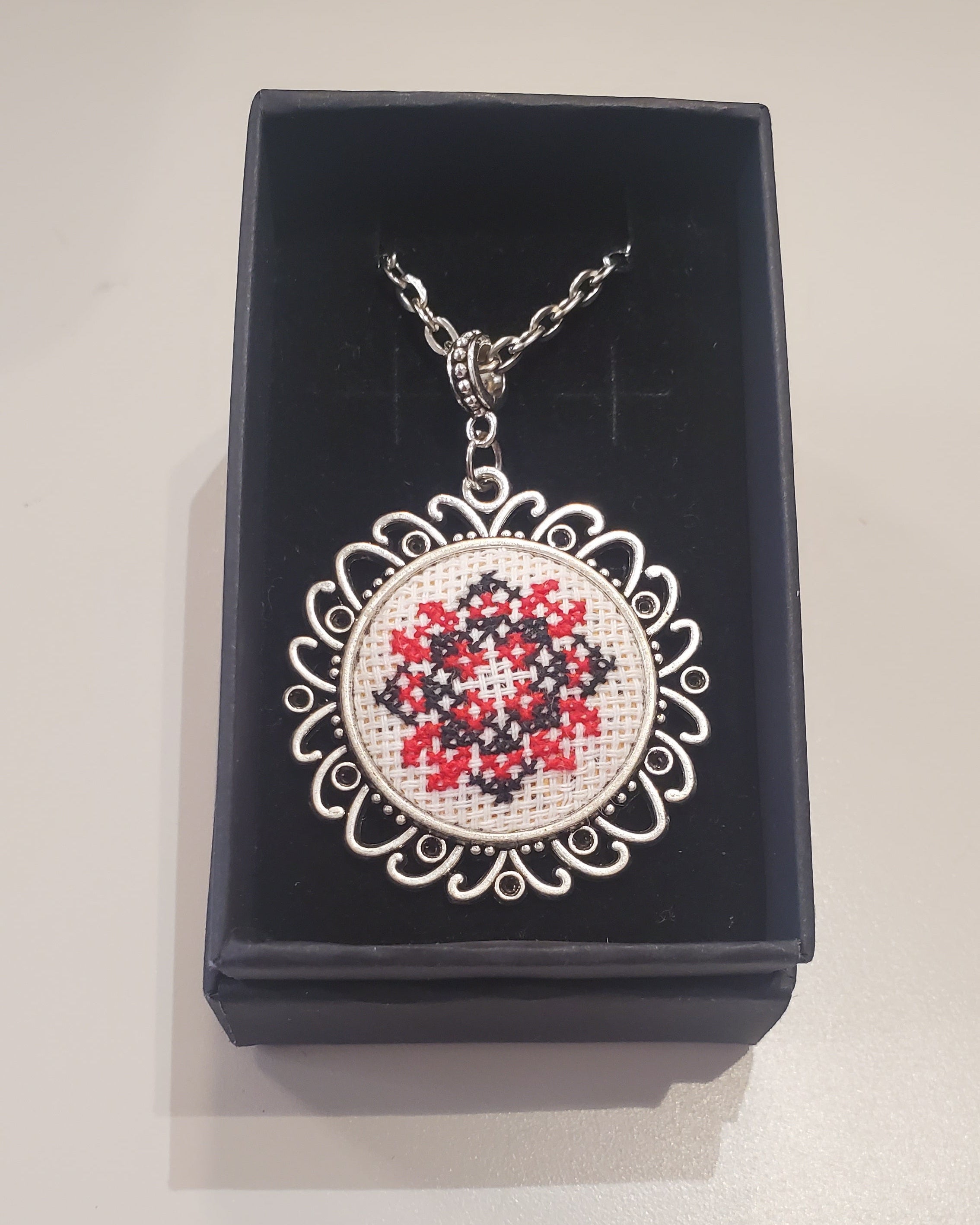 Metal pendant on a rope or chain which micro-embroidered name codes