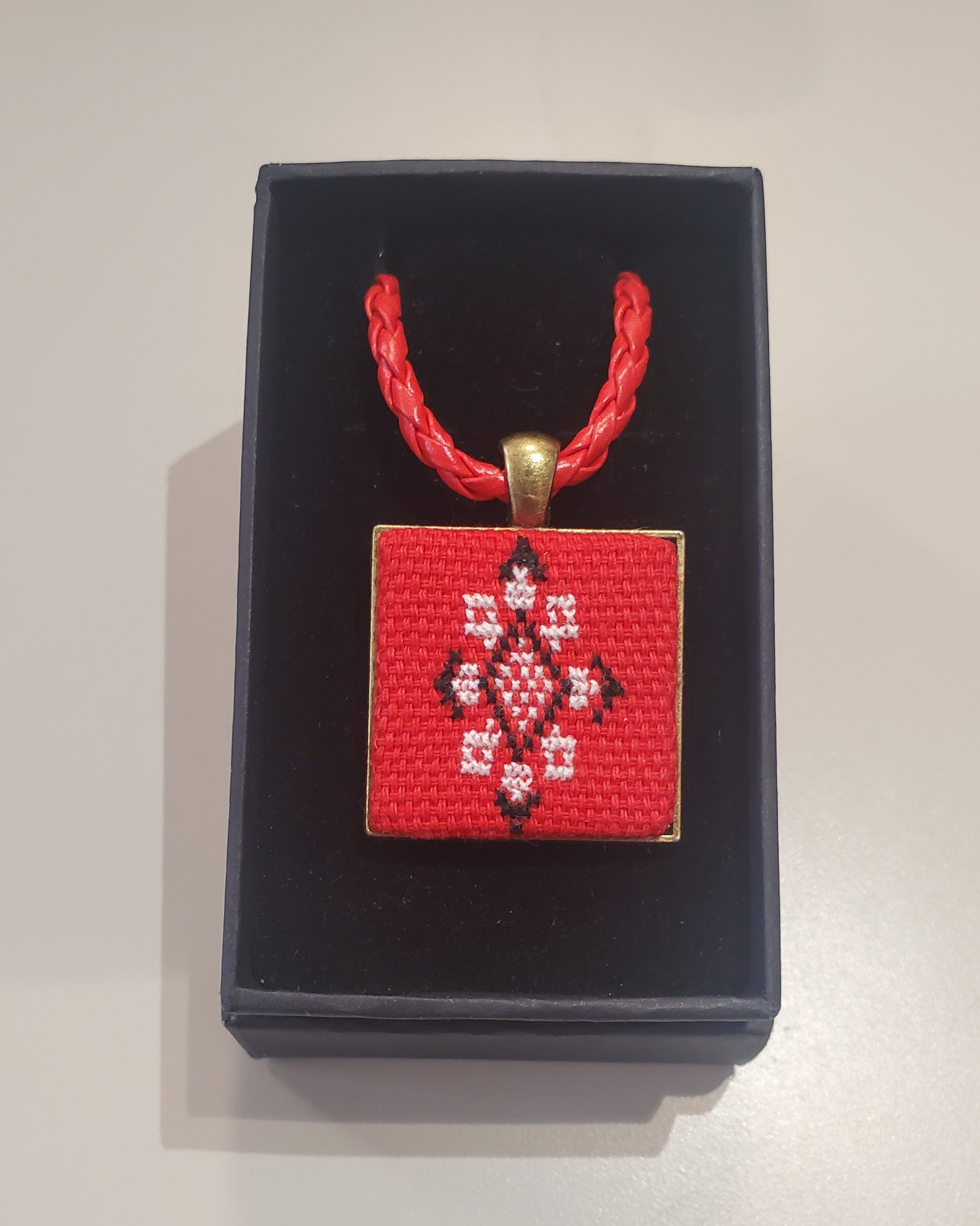 Metal pendant on a rope or chain which micro-embroidered name codes