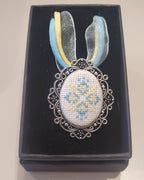 Metal pendant on a rope or chain which micro-embroidered name codes