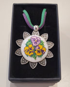 Metal pendant on a rope or chain which micro-embroidered name codes