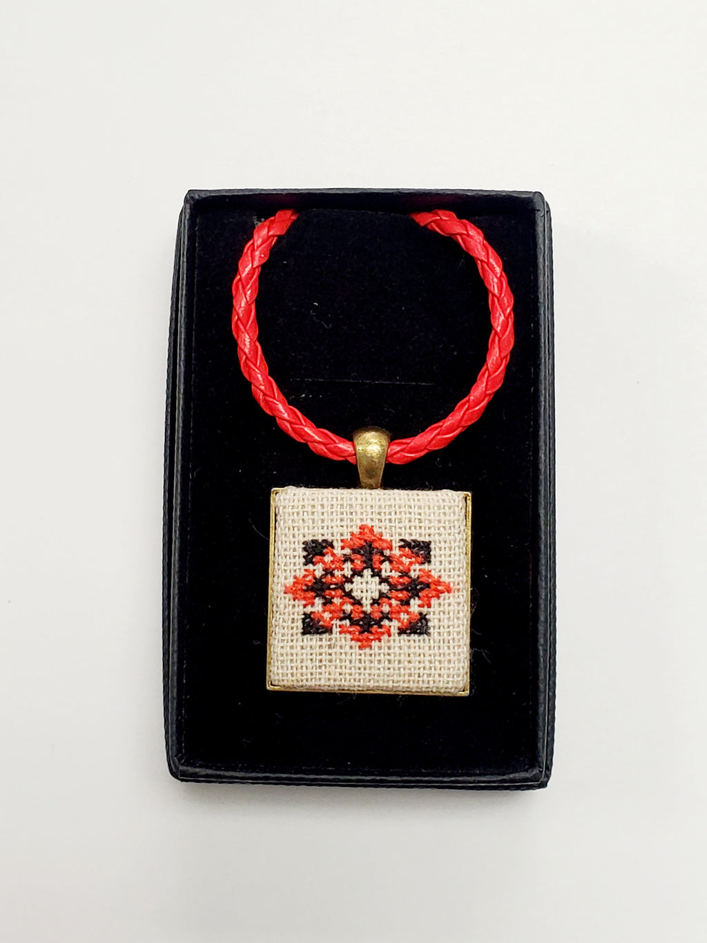 Metal pendant on a rope or chain which micro-embroidered name codes